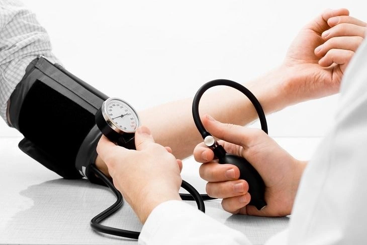 Doctor checking a patient's blood pressure and pulse with a stethoscope